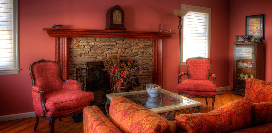 Foto de salón para visitas cerrado clásico de tamaño medio sin televisor con paredes rojas, suelo de madera en tonos medios, todas las chimeneas y marco de chimenea de piedra