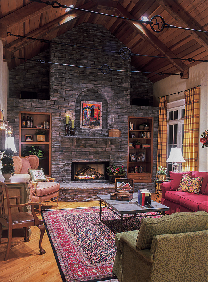 Large rustic enclosed living room in Charlotte with beige walls, light hardwood flooring, a standard fireplace, a stone fireplace surround and no tv.