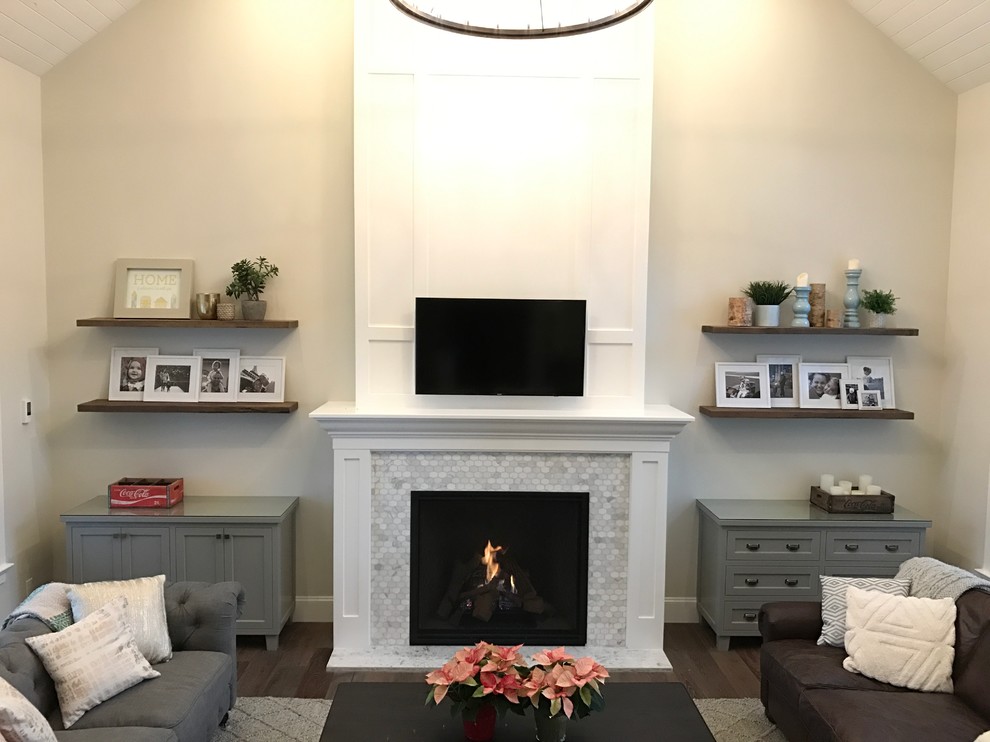 На фото: гостиная комната среднего размера в стиле неоклассика (современная классика) с бежевыми стенами, темным паркетным полом, стандартным камином, фасадом камина из плитки, телевизором на стене и коричневым полом