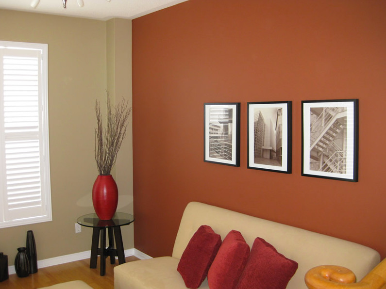 Cette image montre un salon design de taille moyenne et fermé avec un mur orange et un sol en bois brun.