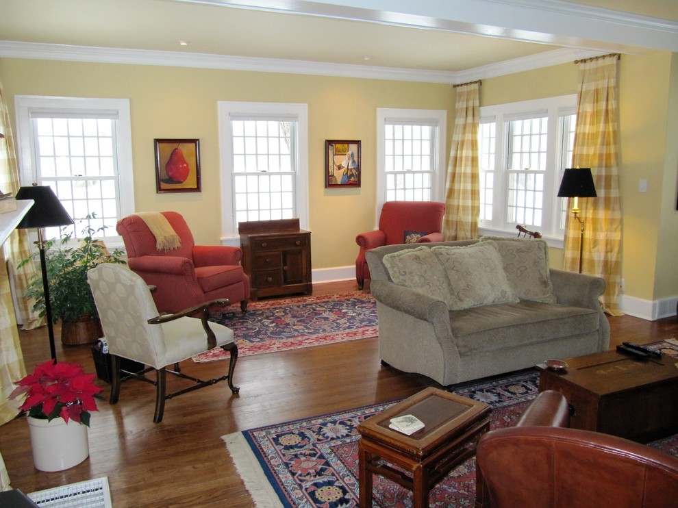 Mittelgroßes, Repräsentatives, Offenes, Fernseherloses Klassisches Wohnzimmer mit gelber Wandfarbe, braunem Holzboden und braunem Boden in Sonstige