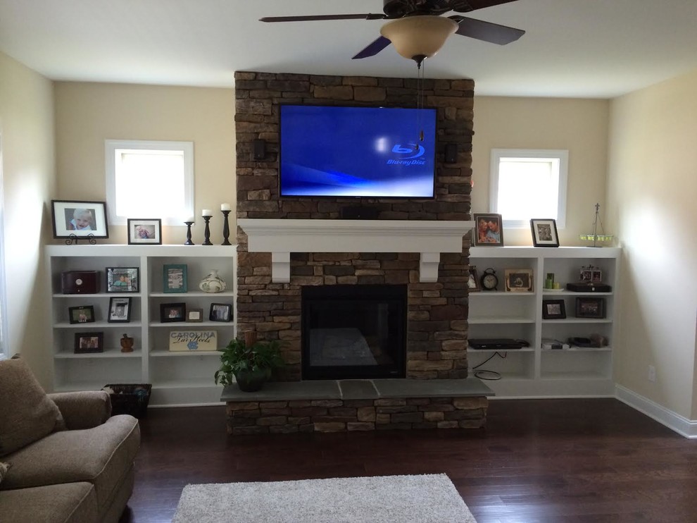 Mid-sized elegant open concept dark wood floor living room photo in Raleigh with beige walls, a standard fireplace, a stone fireplace and a wall-mounted tv