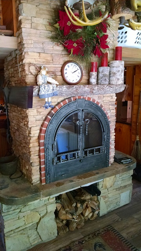 Imagen de salón cerrado tradicional de tamaño medio con suelo de contrachapado, estufa de leña y marco de chimenea de piedra