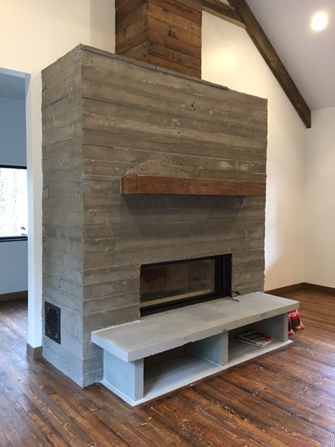 Photo of a medium sized industrial formal enclosed living room in Seattle with yellow walls, dark hardwood flooring, a standard fireplace, a concrete fireplace surround, no tv and brown floors.
