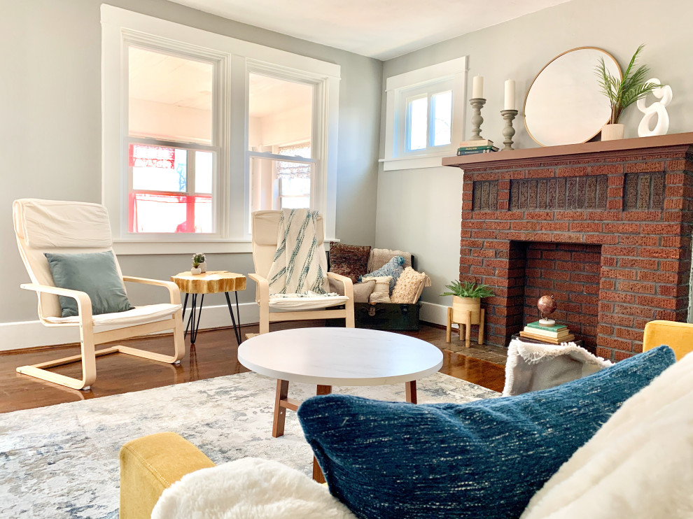 Cette image montre un salon design de taille moyenne avec un mur gris, un sol en bois brun, une cheminée standard, un manteau de cheminée en brique, aucun téléviseur et un sol marron.