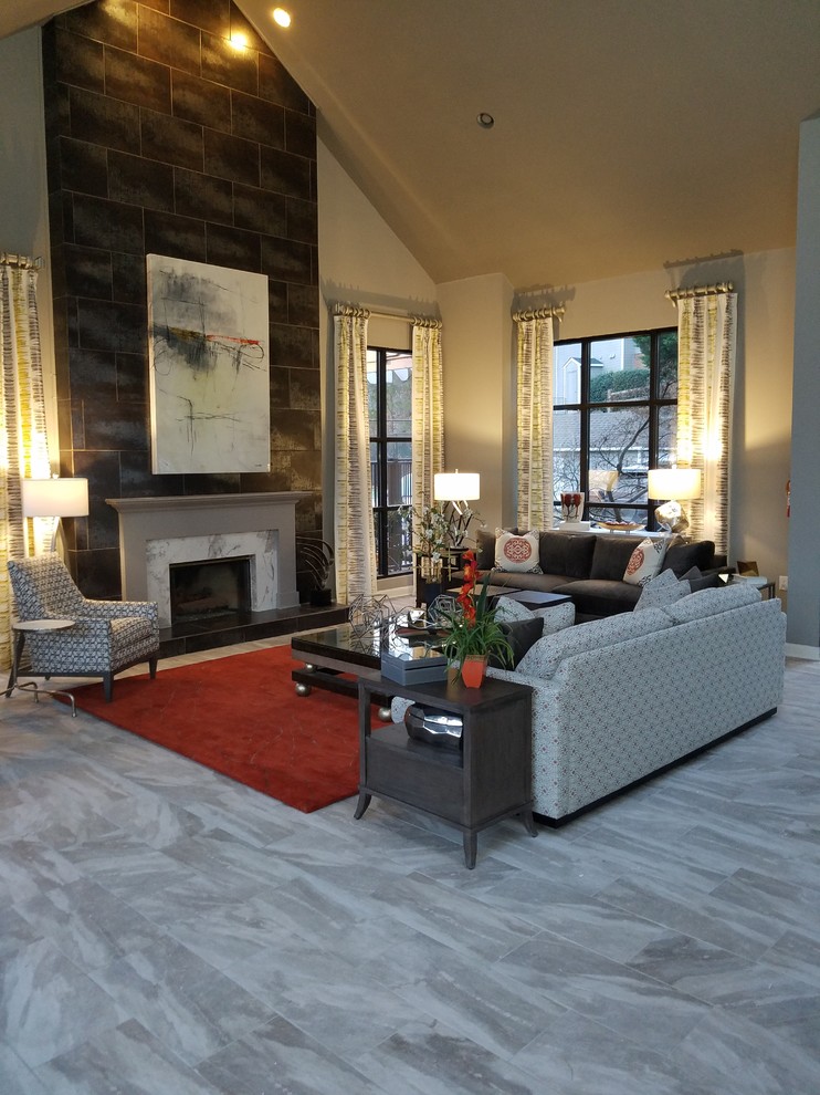 Inspiration for a large world-inspired open plan living room in Atlanta with grey walls, porcelain flooring, a standard fireplace, a tiled fireplace surround, a wall mounted tv and grey floors.