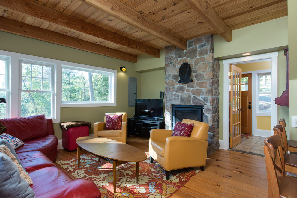 Aménagement d'un salon montagne de taille moyenne et fermé avec un mur beige, un sol en bois brun, une cheminée standard, un manteau de cheminée en pierre, un téléviseur indépendant et un sol marron.