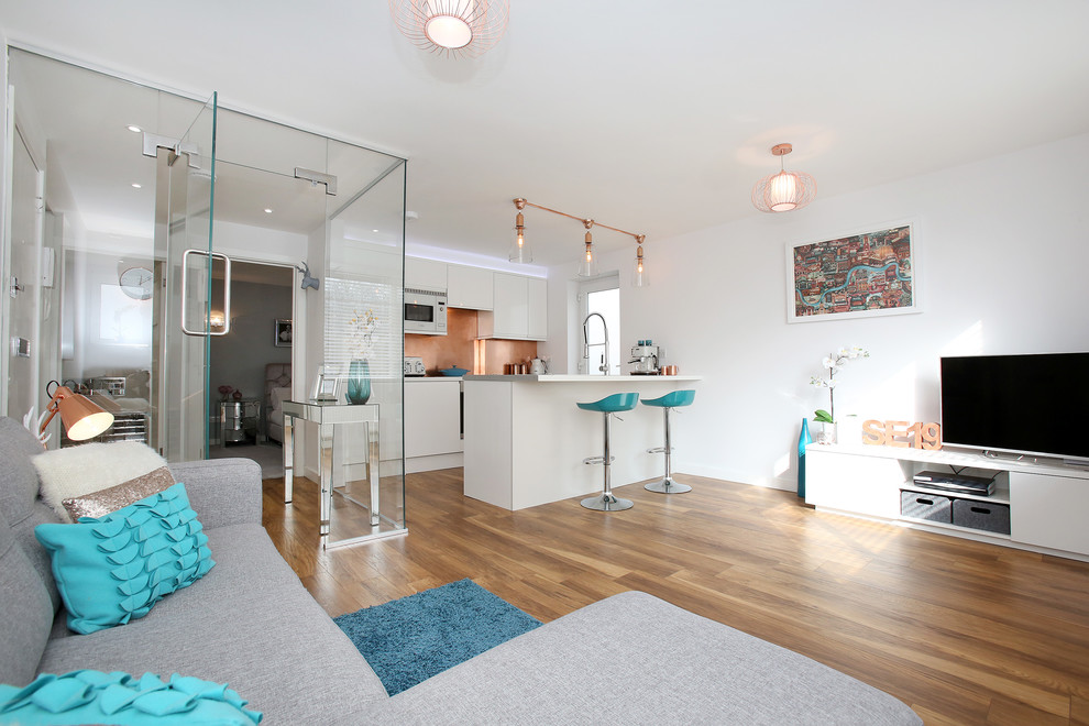Offenes Modernes Wohnzimmer mit weißer Wandfarbe, Laminat und freistehendem TV in London