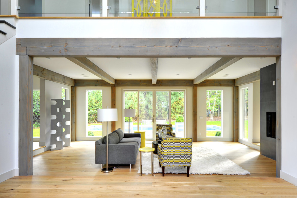 Aménagement d'un grand salon contemporain ouvert avec un mur gris, parquet clair et cheminée suspendue.