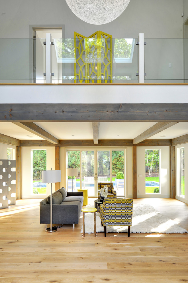 Cette image montre un grand salon design ouvert avec un mur gris, parquet clair et cheminée suspendue.
