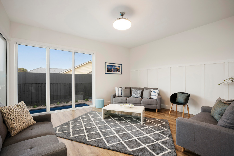 Стильный дизайн: открытая гостиная комната среднего размера в морском стиле с белыми стенами, полом из ламината и коричневым полом без камина, телевизора - последний тренд