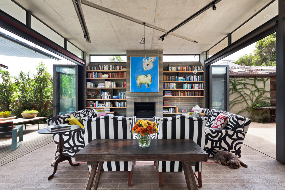 Cette image montre un salon design avec un sol en brique, une bibliothèque ou un coin lecture, une cheminée standard et un manteau de cheminée en brique.