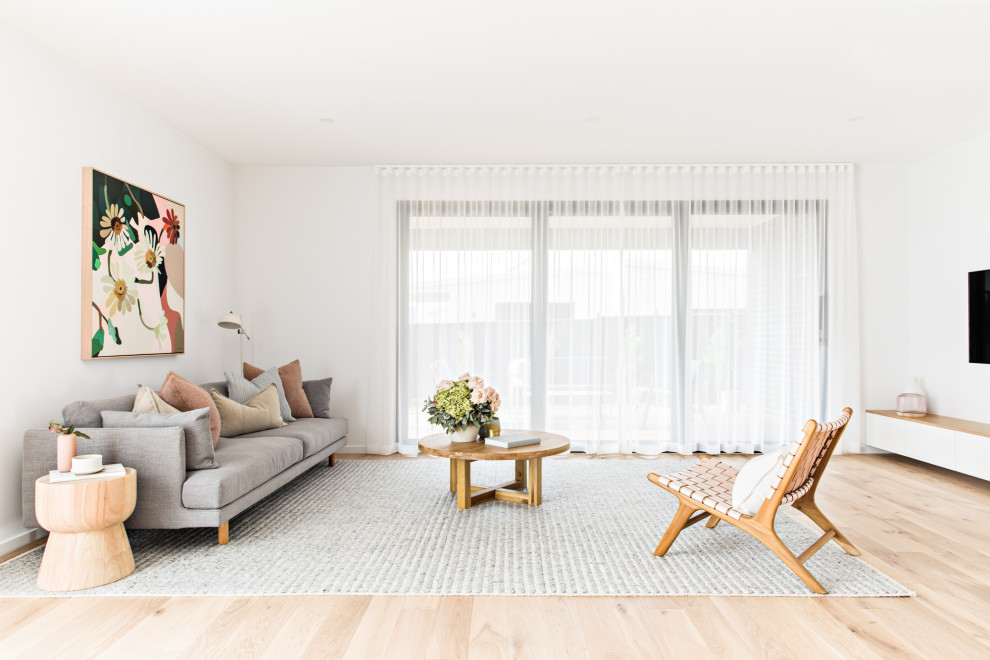 На фото: гостиная комната в скандинавском стиле с белыми стенами, светлым паркетным полом и бежевым полом