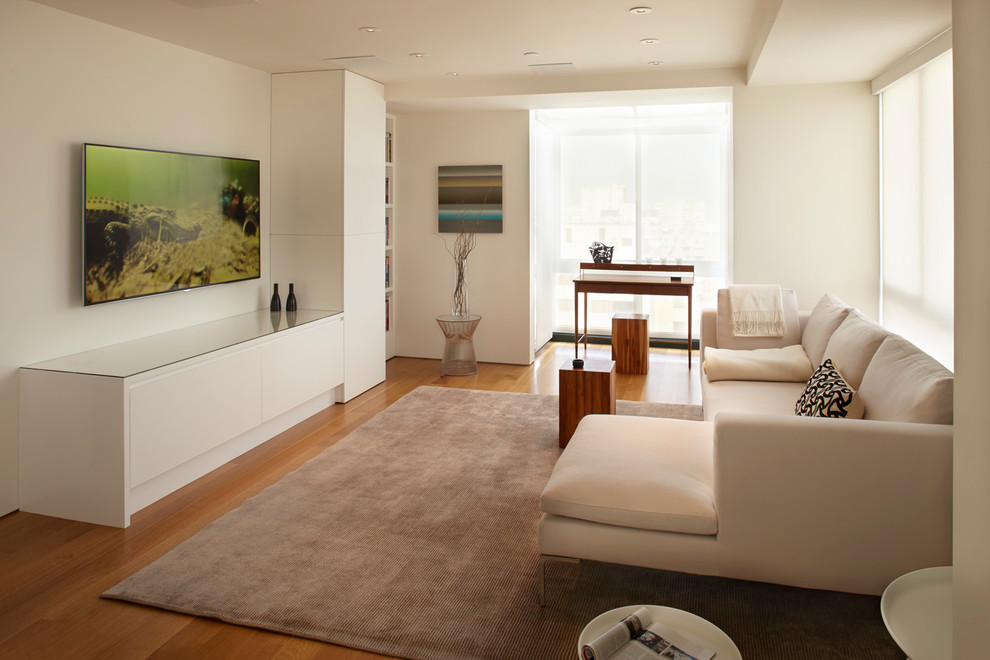 Foto di un soggiorno design con pareti bianche, pavimento in legno massello medio e TV a parete