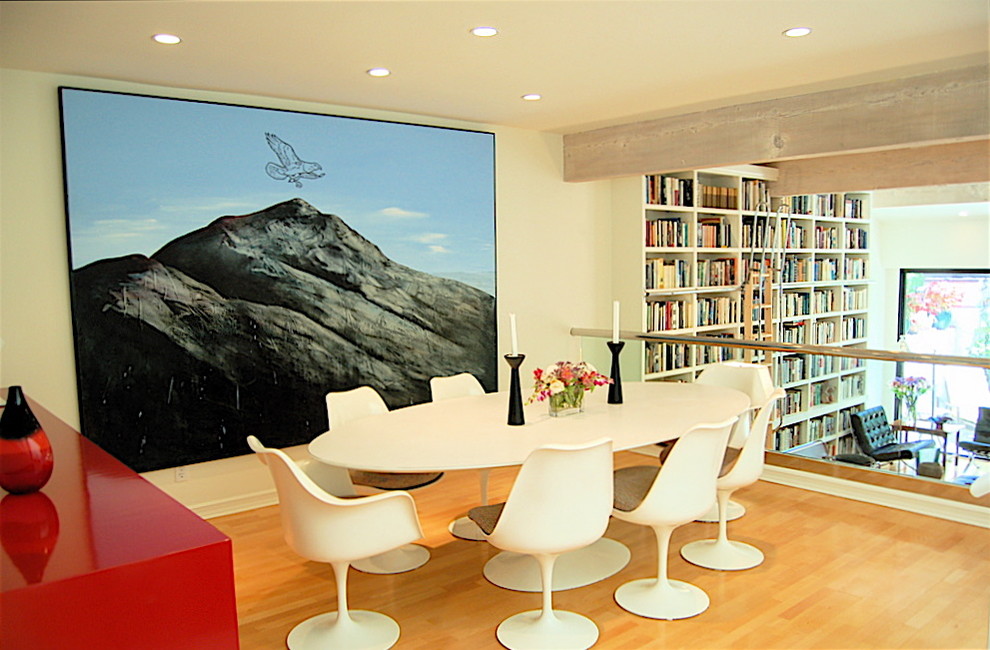 Bild på ett mellanstort funkis allrum med öppen planlösning, med ett bibliotek, vita väggar och ljust trägolv