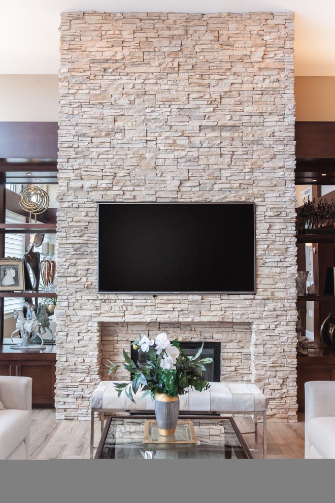 Bild på ett funkis vardagsrum, med beige väggar, en standard öppen spis, en spiselkrans i sten, en väggmonterad TV och beiget golv