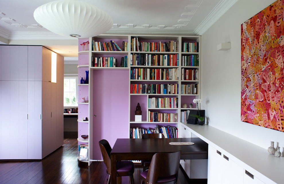 Bild på ett funkis vardagsrum, med ett bibliotek och lila väggar