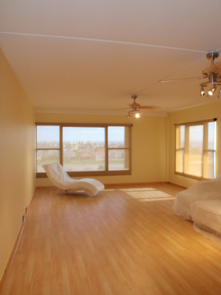 Свежая идея для дизайна: открытая гостиная комната среднего размера в современном стиле с желтыми стенами, полом из ламината и отдельно стоящим телевизором - отличное фото интерьера