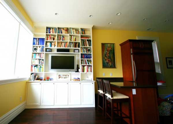 Foto di un grande soggiorno contemporaneo chiuso con libreria, pareti gialle, parquet scuro, nessun camino e TV a parete
