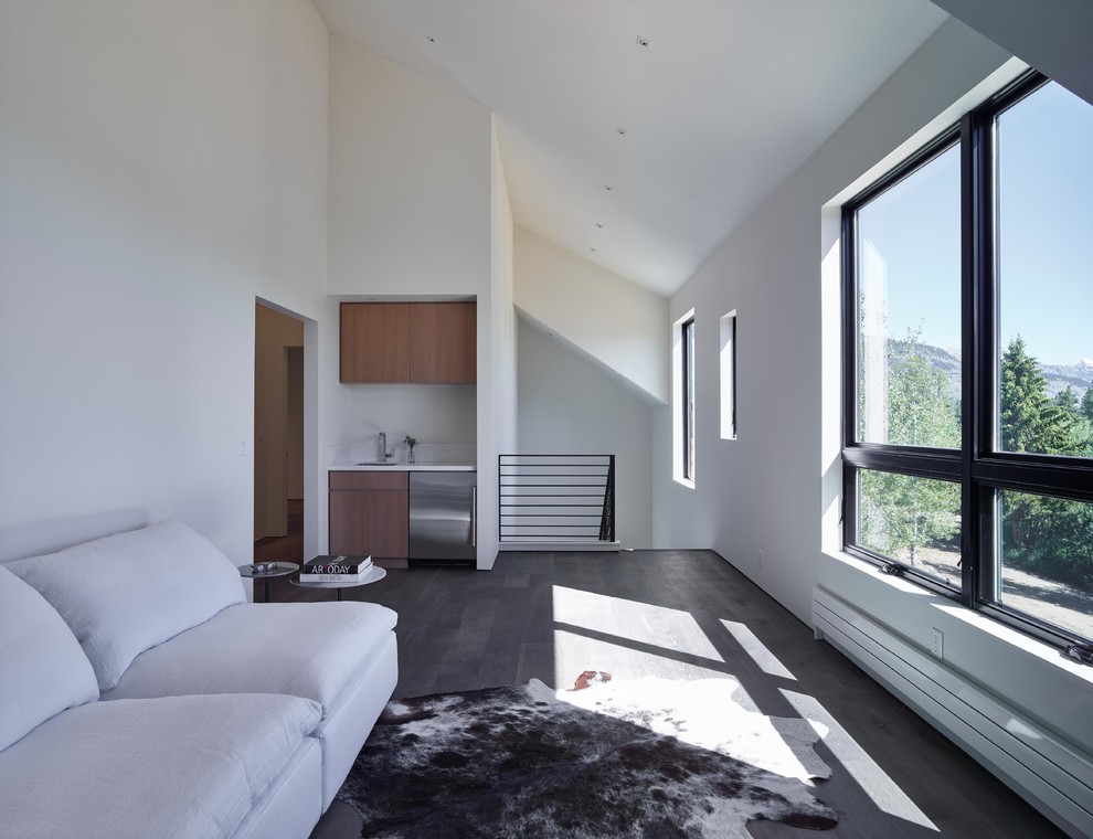 На фото: двухуровневая гостиная комната в современном стиле с белыми стенами и темным паркетным полом