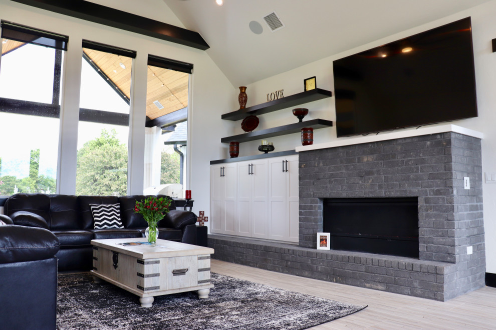 Example of a minimalist open concept ceramic tile living room design in Oklahoma City with white walls, a brick fireplace and a wall-mounted tv