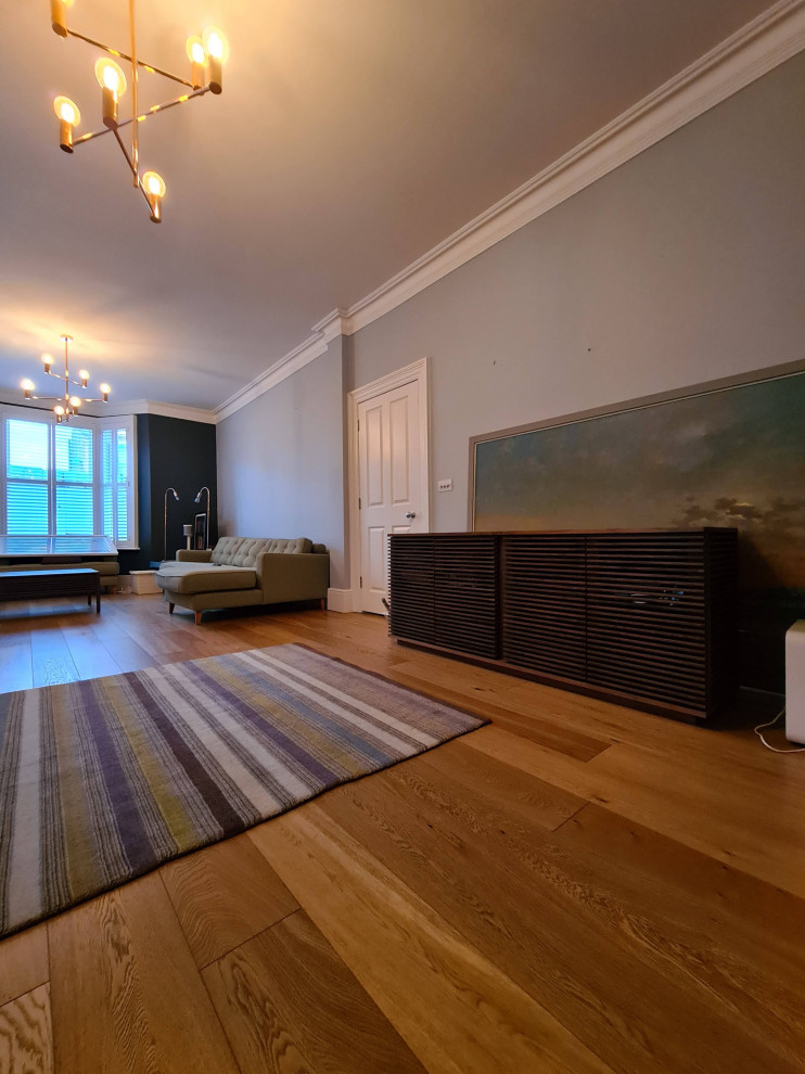 This is an example of a large scandi formal open plan living room in London with grey walls, dark hardwood flooring, a standard fireplace, a stone fireplace surround, a freestanding tv, brown floors and a drop ceiling.