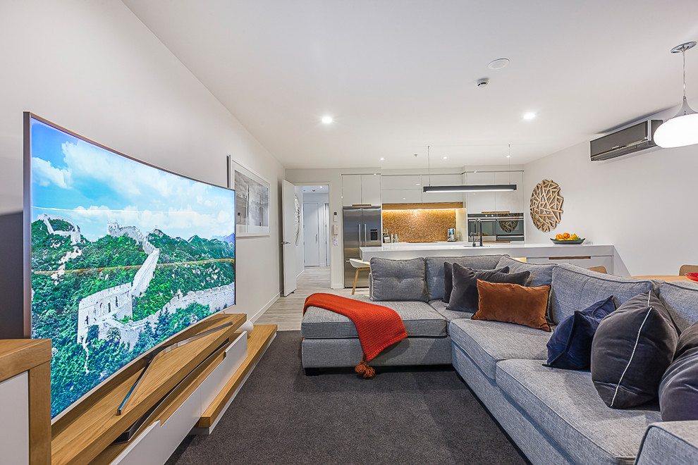 Mid-sized trendy open concept carpeted and brown floor living room photo in Auckland with white walls and a tv stand