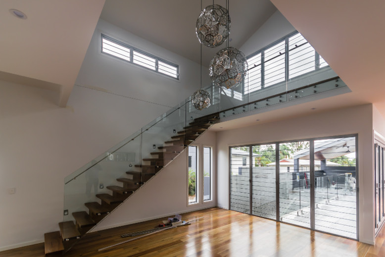 Offenes Modernes Wohnzimmer ohne Kamin mit weißer Wandfarbe und braunem Holzboden in Brisbane