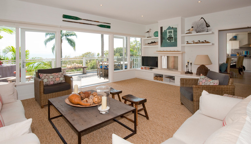 Aménagement d'un grand salon bord de mer fermé avec un mur blanc, moquette, une cheminée standard, un manteau de cheminée en pierre, un téléviseur indépendant et une salle de réception.