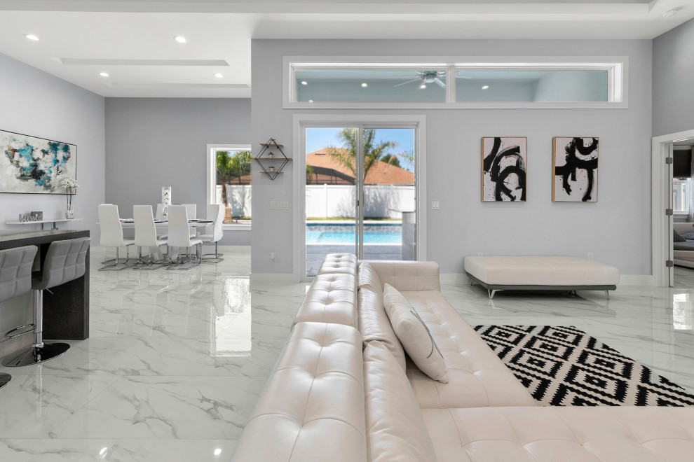 Cette image montre un salon marin avec un mur gris, un sol en marbre, une cheminée standard, un manteau de cheminée en carrelage, un téléviseur encastré, un sol gris et un plafond décaissé.