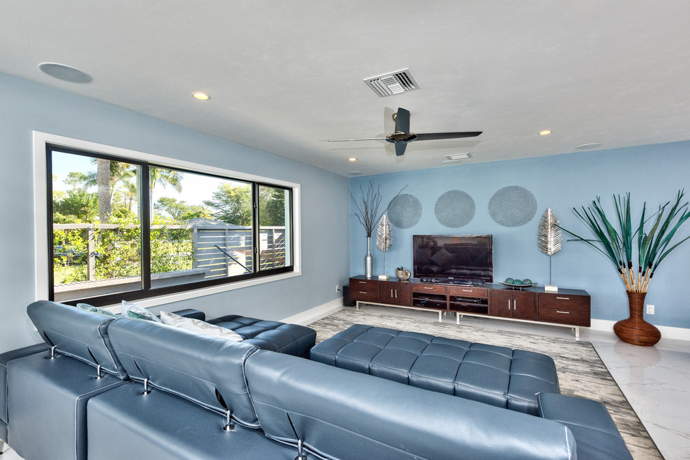 Example of a large beach style open concept marble floor and gray floor living room design in Miami with blue walls, no fireplace and a tv stand