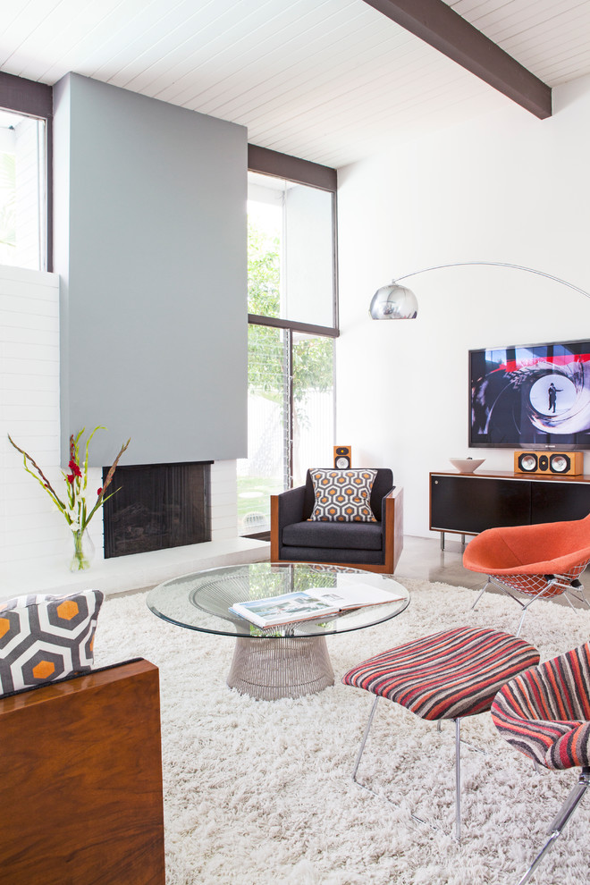 Свежая идея для дизайна: гостиная комната в стиле ретро с белыми стенами, бетонным полом, стандартным камином и серым полом - отличное фото интерьера