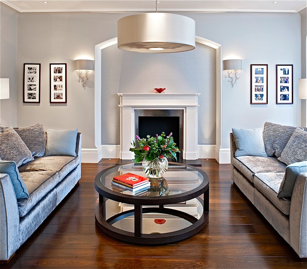 Стильный дизайн: гостиная комната в стиле неоклассика (современная классика) с серыми стенами, стандартным камином и коричневым полом - последний тренд