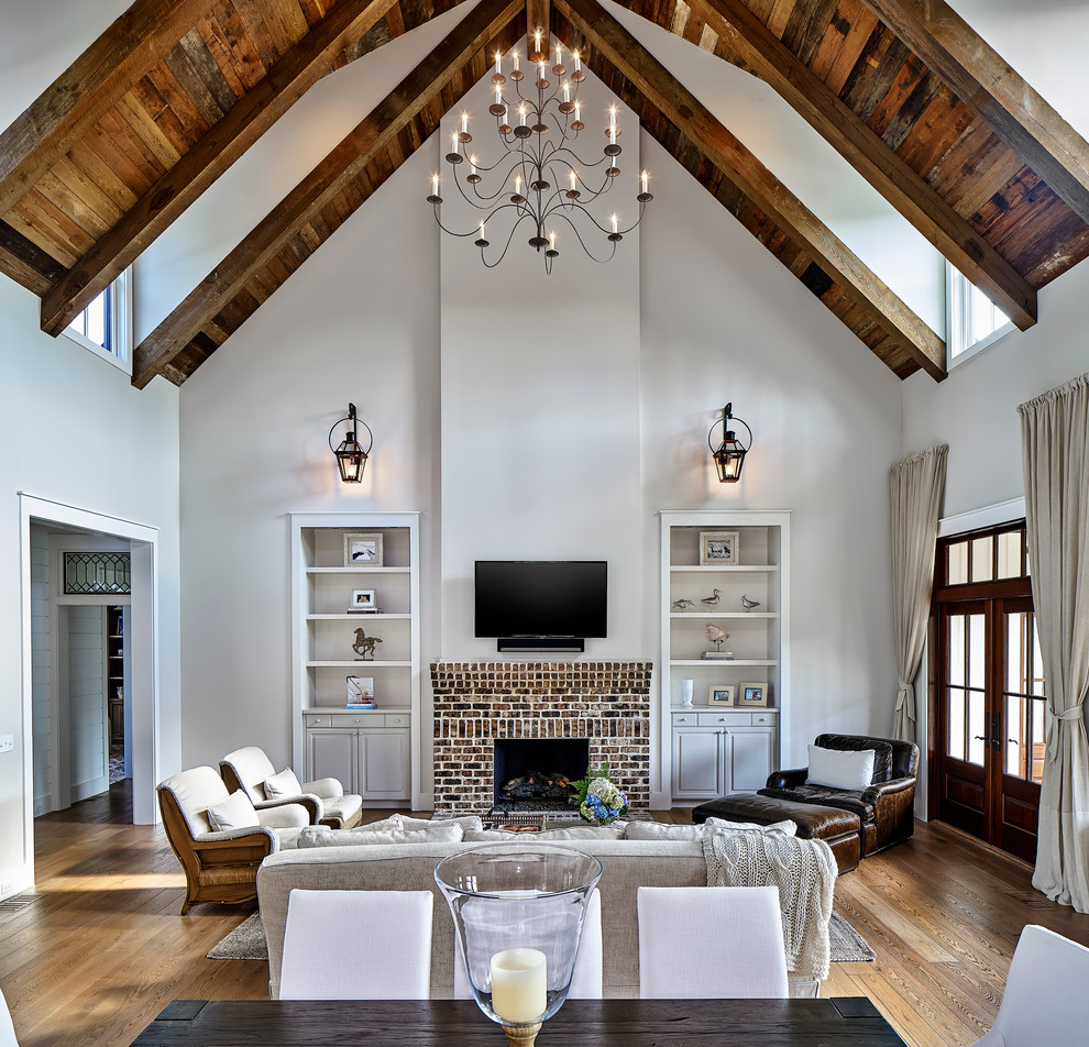Photo of a large farmhouse open plan living room in Atlanta with grey walls, light hardwood flooring, a standard fireplace, a brick fireplace surround, a wall mounted tv and brown floors.