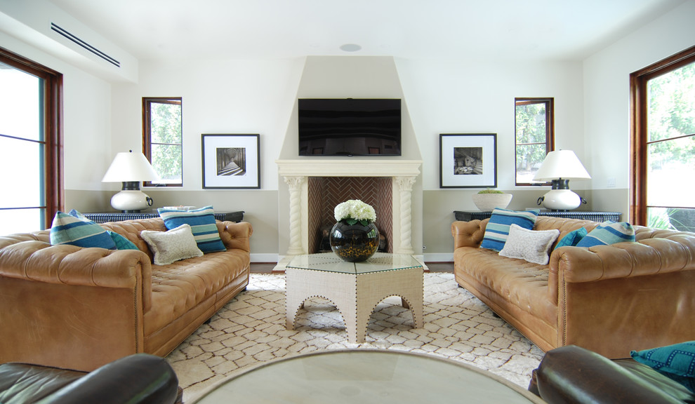 Cette photo montre un grand salon méditerranéen avec un sol en bois brun, une cheminée standard, un manteau de cheminée en pierre et un téléviseur fixé au mur.