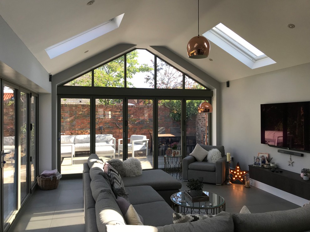 Immagine di un piccolo soggiorno moderno aperto con pareti grigie, pavimento in gres porcellanato, TV a parete e pavimento grigio