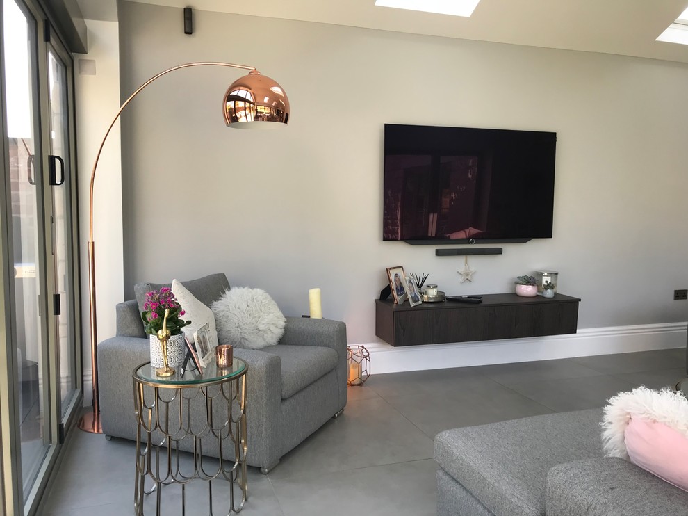 На фото: маленькая открытая гостиная комната в стиле модернизм с серыми стенами, полом из керамогранита, телевизором на стене и серым полом для на участке и в саду