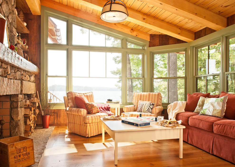 Cette image montre un salon chalet avec un sol en bois brun, une cheminée standard, un manteau de cheminée en pierre et aucun téléviseur.