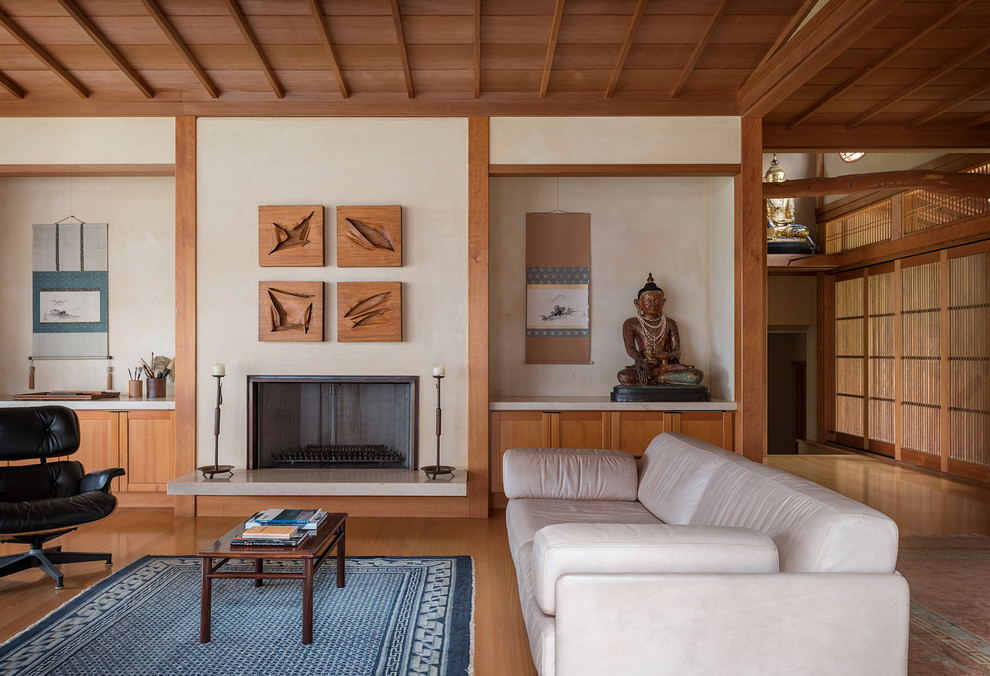 Großes, Fernseherloses, Offenes Asiatisches Wohnzimmer mit beiger Wandfarbe, hellem Holzboden, Kamin, Kaminumrandung aus Metall und braunem Boden in Hawaii