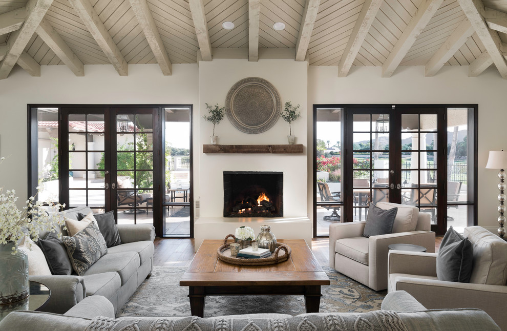 Photo of a mediterranean formal living room in Phoenix with medium hardwood flooring, a standard fireplace and white walls.