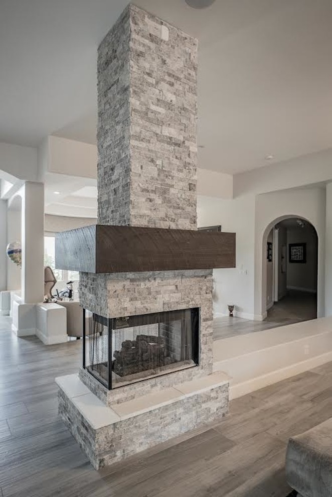 Photo of a small modern open plan living room in Minneapolis with beige walls, porcelain flooring, a two-sided fireplace, a stone fireplace surround and no tv.