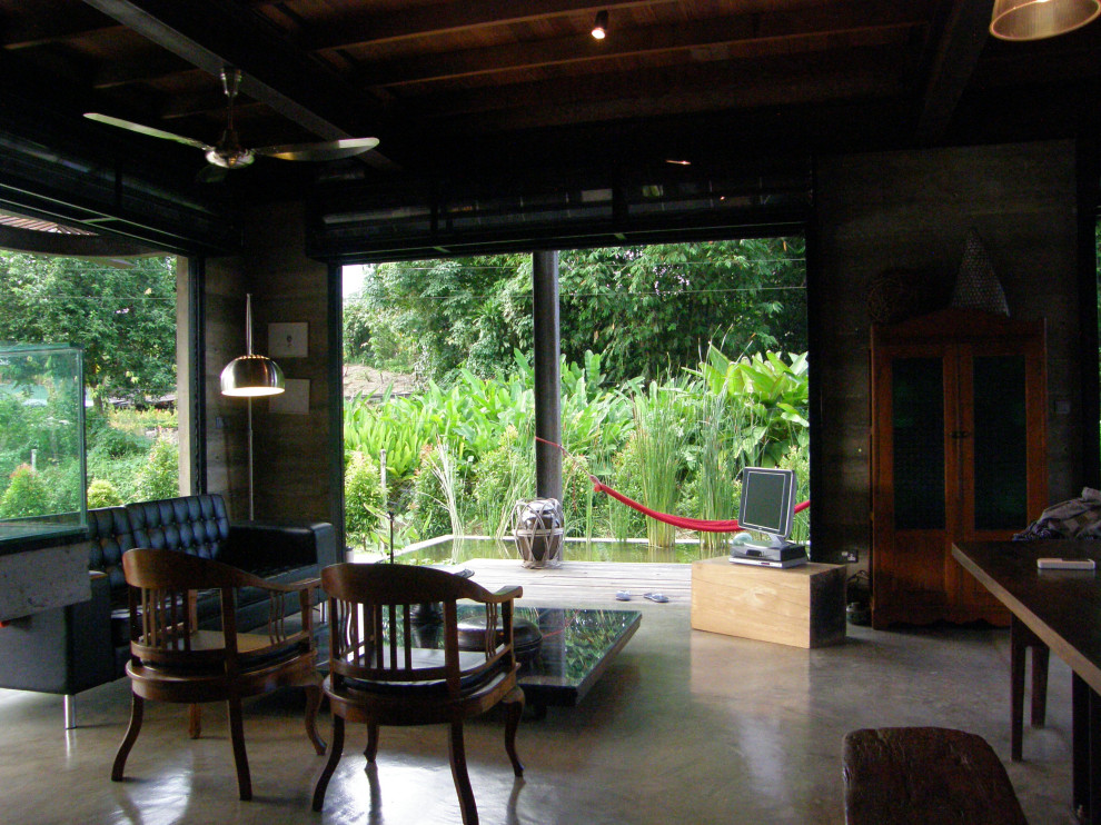 Esempio di un soggiorno tropicale di medie dimensioni e aperto con pareti grigie, pavimento in cemento, nessun camino, TV autoportante e pavimento grigio