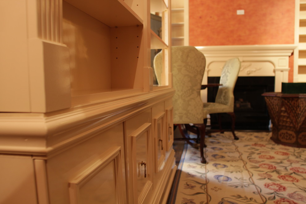 На фото: изолированная гостиная комната среднего размера в классическом стиле с с книжными шкафами и полками, коричневыми стенами, темным паркетным полом, стандартным камином, фасадом камина из дерева и бежевым полом без телевизора с