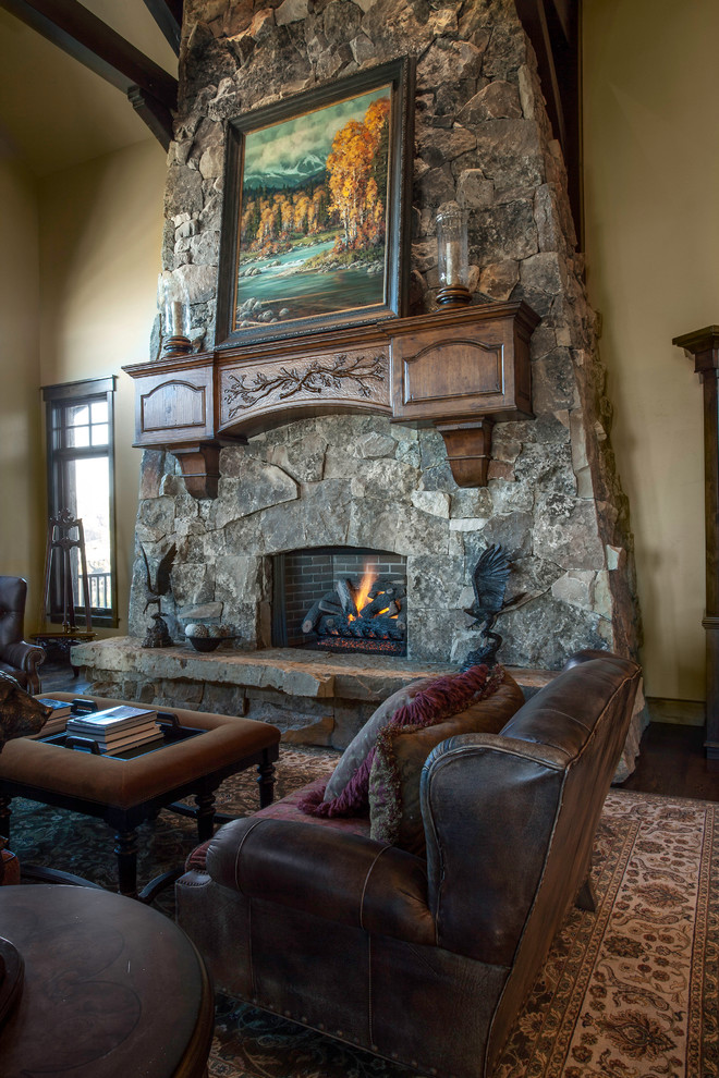 Foto de salón abierto rural extra grande sin televisor con paredes beige, suelo de madera oscura, todas las chimeneas y marco de chimenea de piedra