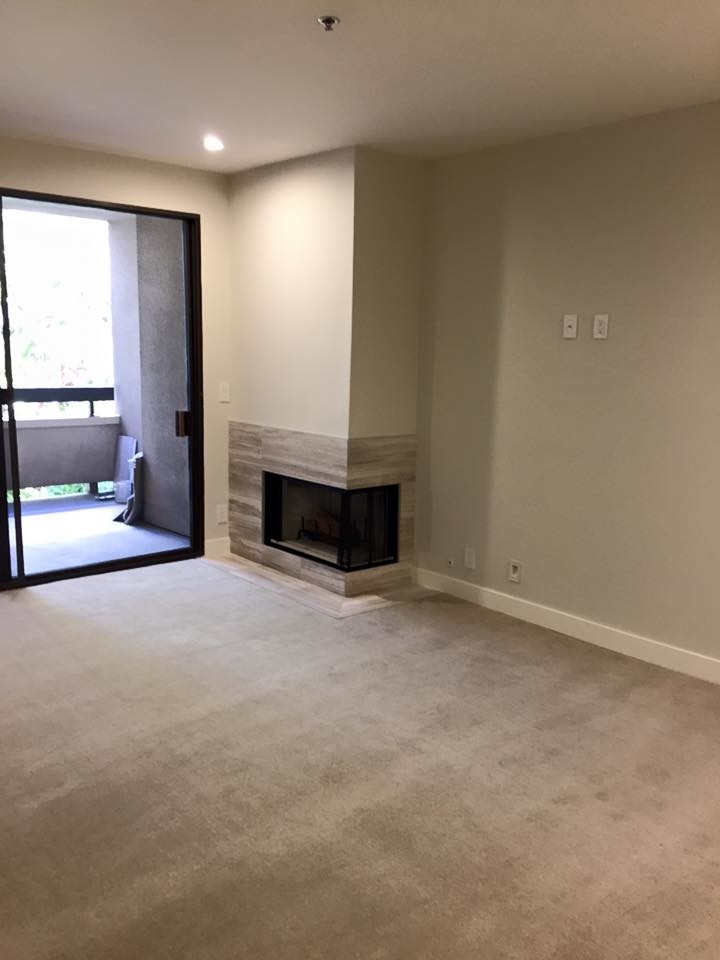Example of a mid-sized minimalist enclosed carpeted living room design in Los Angeles with beige walls, a corner fireplace and a wood fireplace surround
