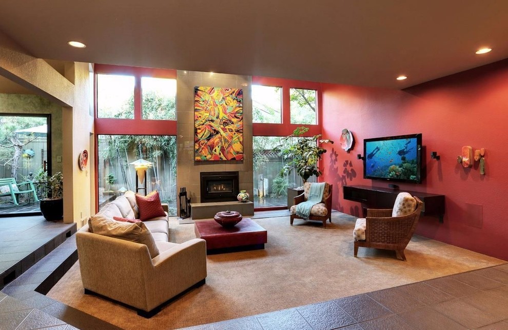 Свежая идея для дизайна: двухуровневая гостиная комната среднего размера в современном стиле с красными стенами, полом из керамической плитки, печью-буржуйкой, фасадом камина из плитки, телевизором на стене и черным полом - отличное фото интерьера