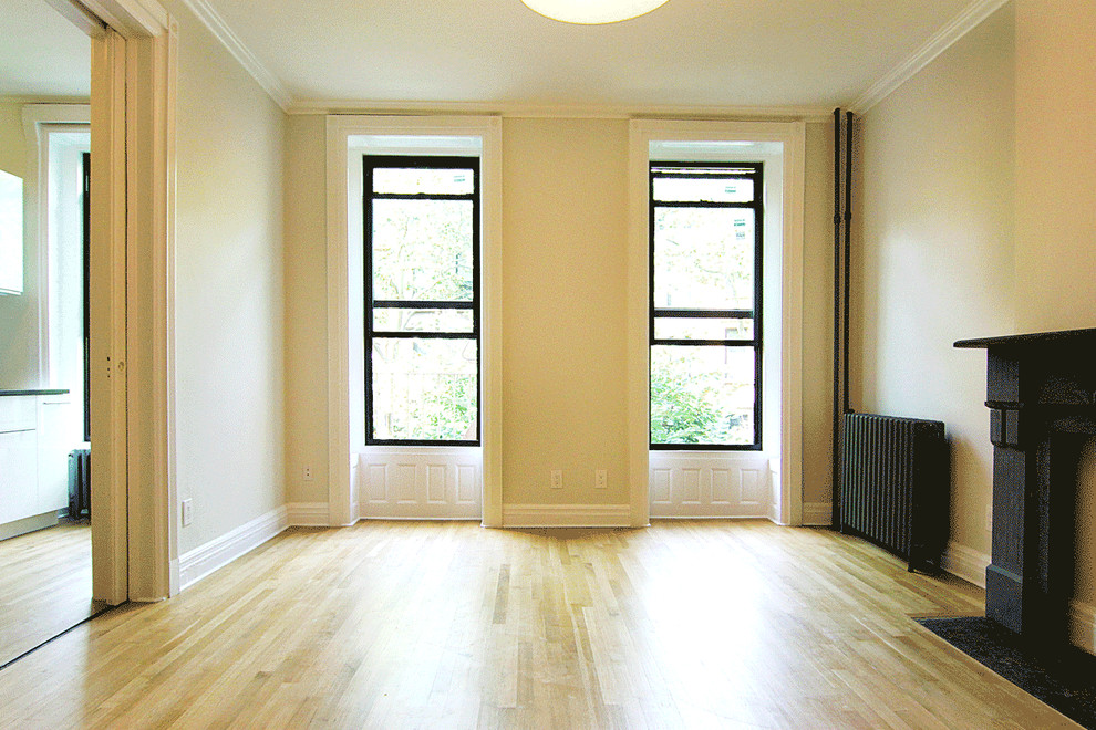 Photo of a small contemporary formal enclosed living room in New York with beige walls, light hardwood flooring, no fireplace, a stone fireplace surround and no tv.