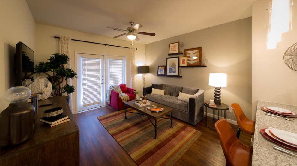 Offenes Industrial Wohnzimmer ohne Kamin mit beiger Wandfarbe und braunem Holzboden in Houston