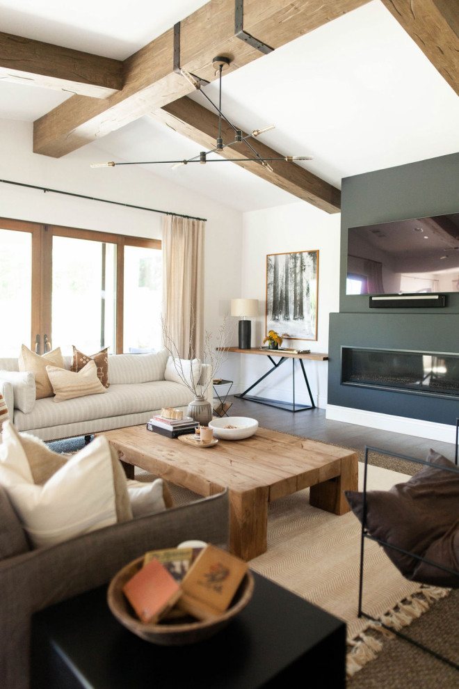 Diseño de salón abierto de estilo de casa de campo con paredes blancas, suelo de madera oscura, chimenea lineal, televisor colgado en la pared y suelo marrón