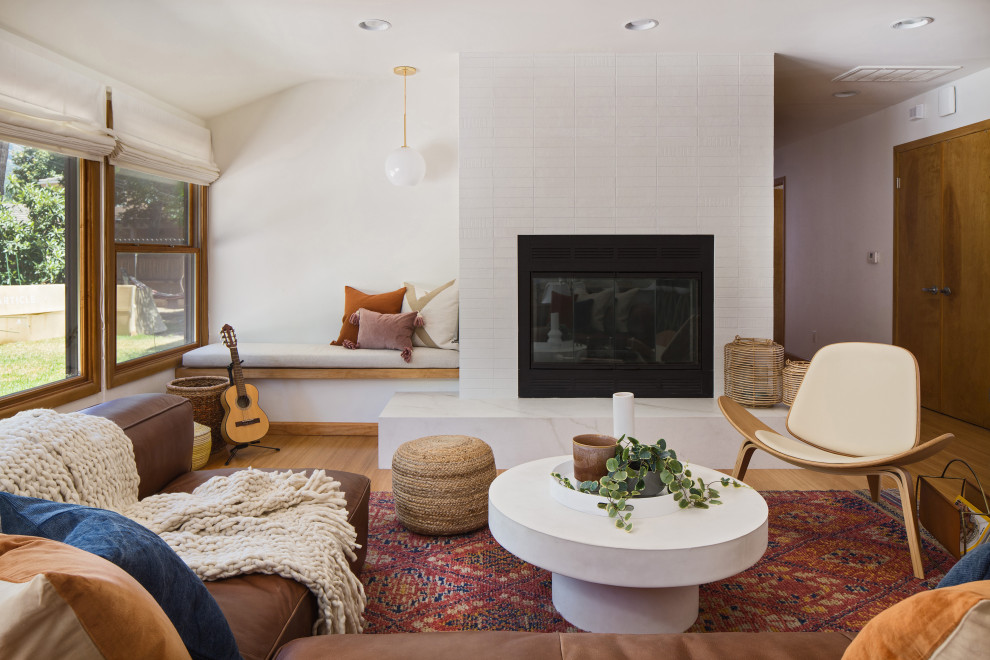 Offenes Retro Wohnzimmer mit weißer Wandfarbe, braunem Holzboden, Kamin, gefliester Kaminumrandung und braunem Boden in Portland